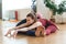 Two sporty girls in gym doing acroyoga, yoga with partner, Wide-Angle Seated Forward Bend, Upavishtha Konasana.