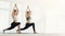 Two sporty women practice yoga in light gym