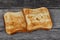 Two square ruddy pieces of bread for toasts on the old gray wooden background