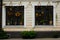 Two square windows with flowers and lamps in the old light-yellow building