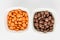 Two squared bowls with small orange and brown coated chocolate candies similar to m&ms in a squared bowl isolated on white backgro