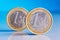 Two standing one euro coins on a blue background