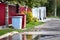 Two steel red and gray painted trash bins of old-fashioned design in backyard along road with puddle as concept of reuse and