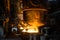 Two steelworkers pours liquid metal into molds from tank