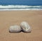 Two stone pebbles with the word beach and anchor sign over sandy beach and sea horizon