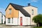 Two storey cottage or bungalow with red door standing in front of camera