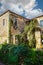 Two story ancient rustic  rock and stucco building overgrown with vines in Greek village of Kardamyl