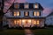 two-story colonial house, symmetrical windows highlighted under twilight