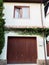 Two-story garage overgrown with ivy with wooden electric lifting gates