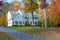 two-story house among autumn trees. Asphalt driveway to garage