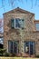 Two story house with french doors and tile roof and extreme rough stucco texture and rustic shutters