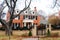 Two story red brick house in upscale leafy residential neighborhood with iron fence and gate beautifully decorated with Christmas