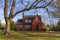 A two story red brick vintage  house in a spacious land with a tall tree on its front yard.