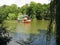 A two-story river ship sweeps swiftly over the watery surface against the backdrop of the green park zone