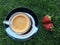 Two strawberrys on the grass with cup of coffee