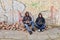 Two street hooligans standing against a graffiti painted wall are preparing to smoke a cigarette