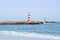 Two striped lighthouses stand on the beach in the city of Faro in Portugal. Little waves in the ocean on a sunny day .