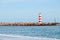 Two striped lighthouses stand on the beach in the city of Faro in Portugal. Little waves in the ocean on a sunny day .