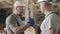 Two strong Caucasian builders in white helmets shaking hands at the construction site. Workers gesturing yes and one man