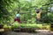 Two strong excited young friends playing outdoors in rope park