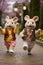 Two stuffed animals dressed in clothes and hats walking down a brick path, AI