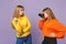 Two stunning young blonde twins sisters girls in colorful clothes taking pictures on retro vintage photo camera isolated