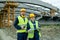 Two successful engineers in workwear standing on construction site