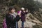 Two successful hiker woman friends enjoy the view on mountain peak. Happy backpackers in nature taking pictures with mobile phone