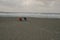 Two sun loungers on a large sandy beach next to a rough sea in cloudy weather