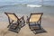 Two sun loungers stand on the sandy beach