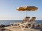 Two sunbeds and one parasol standing at the breakwater with view to the Atlantic Ocean, Puerto Rico on the Canary Island