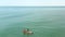 Two surfers floating on supboard in turquoise wave sea. Aerial round view