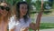 Two surprised girls talking and riding on a swing in a summer park.