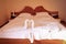 Two swans made of towels forming heart shape on bed in honeymoon suite room hotel decorated