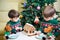 Two sweet boys, brothers, making gingerbread cookies house, decorating at home in front of the Christmas tree, child playing and