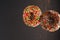 Two sweet donuts decorated with multi-colored confectionery sprinkles on a gray background. Sweet food, breakfast for two,