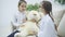 Two sweet kids playing with teddy-bear. The girl who plays a doctor is examining plush bear with stethoscope, talking