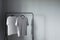 two t-shirts of neutral colors on hanger against gray wall