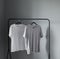 Two t-shirts of neutral colors on  hanger against  gray wall