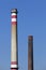 Two tall factory chimneys. Red-white chimney with a gallery