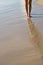 Two tanned women legs walking on sand beach