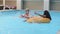 Two tanning sunbathing multiracial Caucasian Hispanic female sitting in tube floating inflatable ring in blue water in