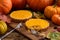 Two tasty pumpkin pies being eaten with fork on wooden board surrounded with orange pumpkins