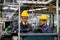 Two technician men with blue uniform and yellow helmet work with the machine in factory