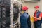 Two technicians in red caps and vests work in the server room. Specialists service the equipment of a modern data center. Men