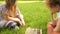 Two teen girlfriends playing chess in the park sitting on the grass. School holidays, intellectual games for teens