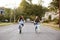 Two teen girls riding bikes in a quiet street, front view