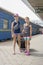 Two teen girls at the train station with a suitcase. Two sisters are pulling a large and heavy black suitcase against the