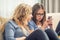 Two teen girs or sisters using smart phones in the living room