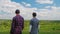 Two teenage boys stand in a picturesque rural place, look at the horizon. Rear view